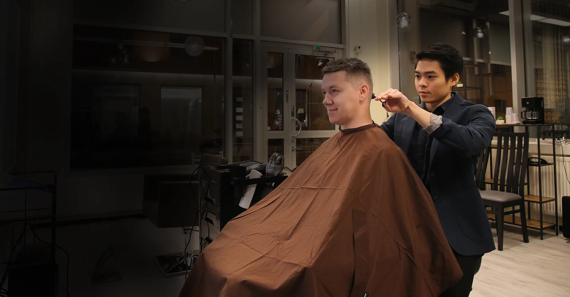 Kampaaja leikkaa asiakkaan hiuksia The 20 Haircuts -liikkeessä Vaasassa